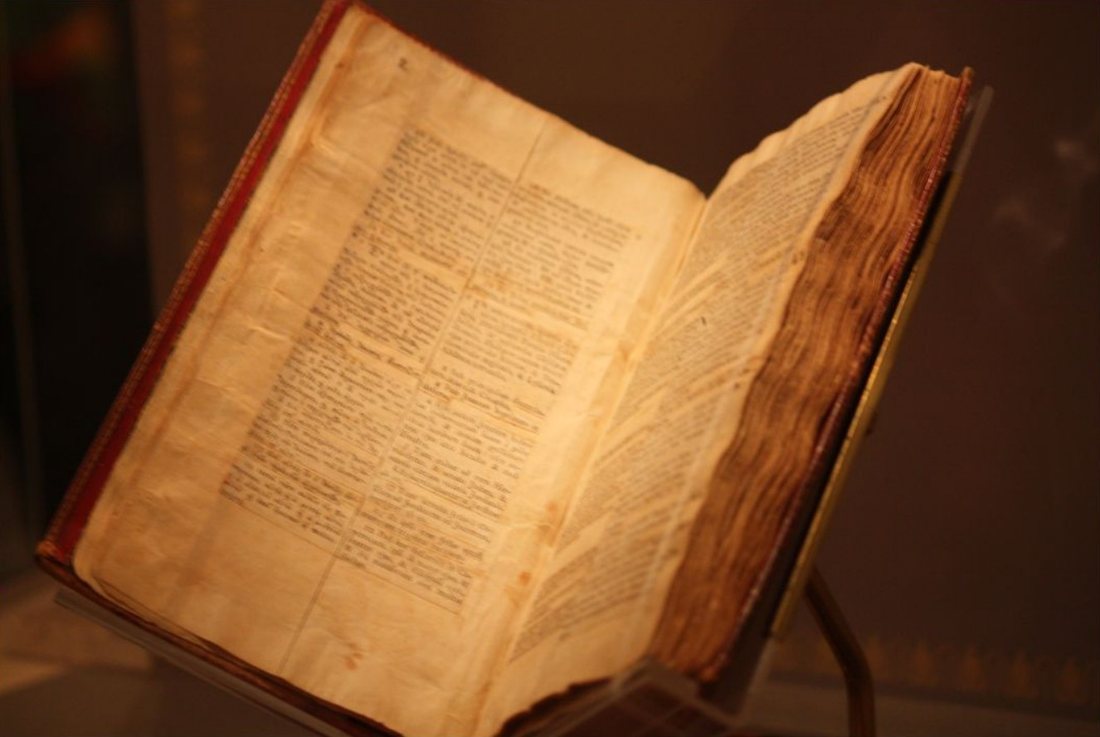 El libro original de Jefferson abierto en su soporte de museo: los vers&iacute;culos que recort&oacute; a mano, pegados en cuatro columnas paralelas de griego, lat&iacute;n, franc&eacute;s e ingl&eacute;s sobre papel envejecido